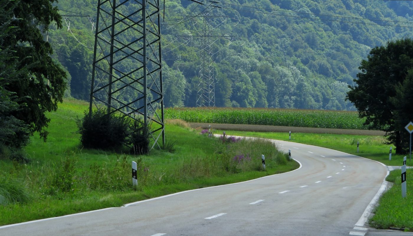 green grass field near gray concrete road