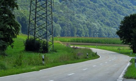 green grass field near gray concrete road