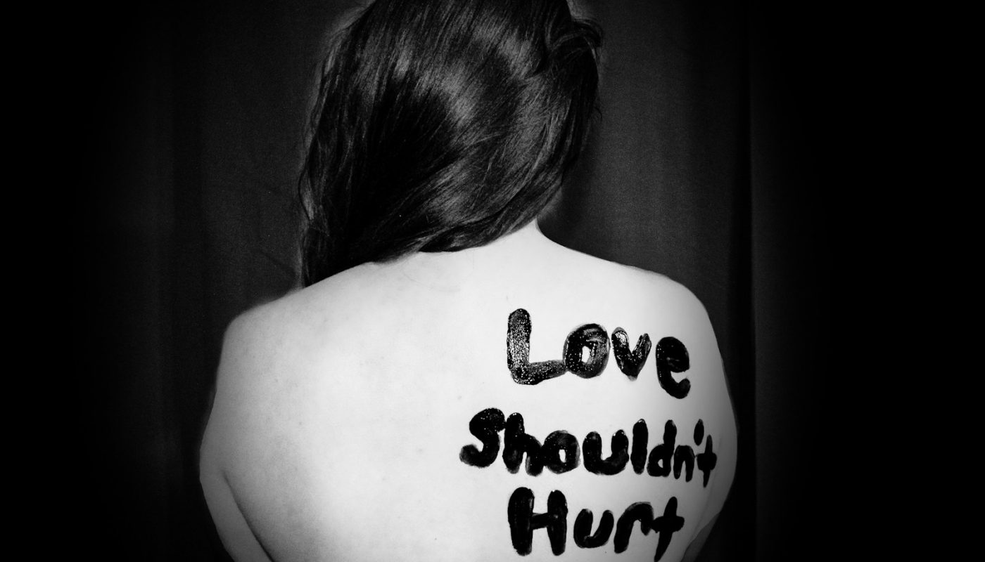 love shouldn't hurt-printed on back of woman