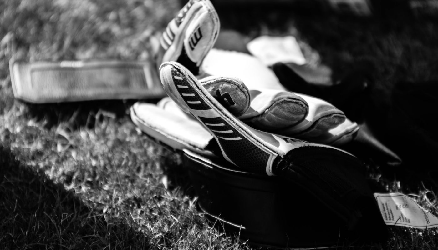 greyscale photo pair of gloves on grass field