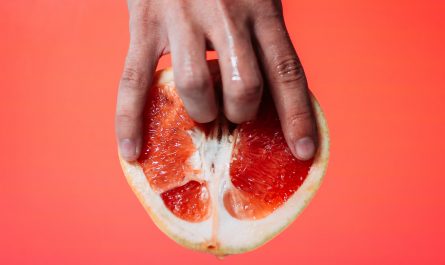 person holding red pomelo fruit