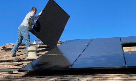 man in white dress shirt and blue denim jeans sitting on white and black solar panel