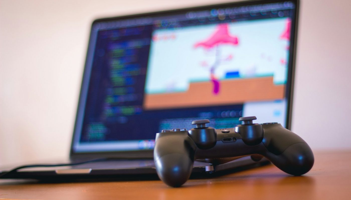 black laptop computer beside controller on brown wooden surface