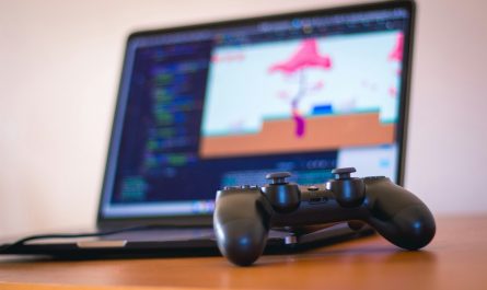 black laptop computer beside controller on brown wooden surface